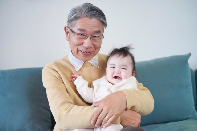 生まれたばかりの孫を抱きあげ笑顔の祖父